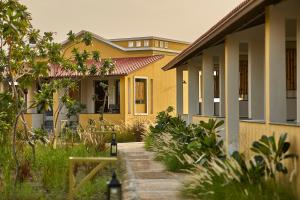 een geel huis met een pad ervoor bij Blackbuck Safari Lodge Velavadar in Velavadar