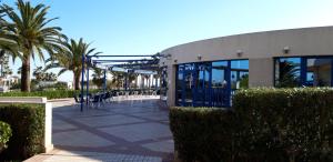 un edificio con mesas, sillas y palmeras en PATACONA BEACH, en Valencia