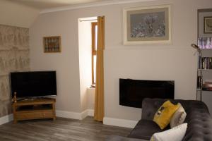 a living room with a couch and a flat screen tv at Buttermere Cottage in Banff