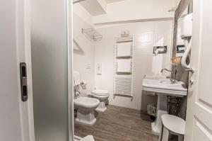 - une salle de bains blanche avec 2 toilettes et un lavabo dans l'établissement Spazio San Marco, à Bergame