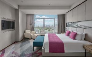 Crowne Plaza Manila Galleria, an IHG Hotel في مانيلا: غرفة فندقية بسرير كبير ونافذة كبيرة