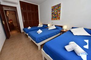 Duas camas num quarto com lençóis azuis e almofadas brancas em Costamar 13 em Es Pujols