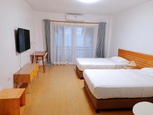 een hotelkamer met drie bedden en een televisie bij sunny islander diving resort in Looc