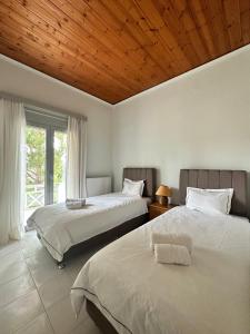 two beds in a bedroom with a wooden ceiling at Mata's Spacious Apartment in Astros