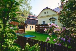 a house with a yard with a fence and flowers at Apartmány Na Faře in Bílá