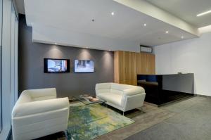 a living room with two white chairs and a tv at Les Immeubles Charlevoix - Le 760-506 in Quebec City