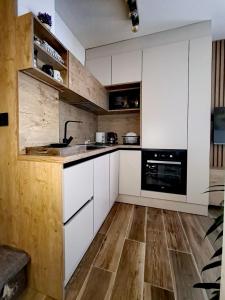 eine Küche mit weißen Schränken und Holzböden in der Unterkunft Apartman 12 - Jahorina in Jahorina