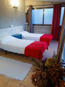 duas camas com lençóis vermelhos e brancos num quarto em Albergue Villa San Clemente em Tui
