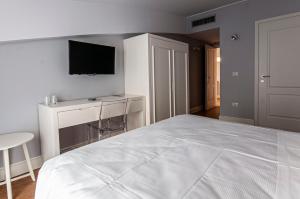 1 dormitorio con 1 cama blanca y TV en la pared en Spazio San Marco en Bérgamo