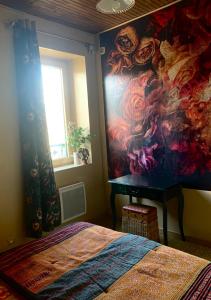 a bedroom with a painting on the wall next to a bed at La Passerelle in Loguivy-Plougras