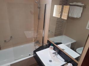 ein Badezimmer mit einem Waschbecken, einer Badewanne und einem Spiegel in der Unterkunft Castilla Guerrero in Málaga