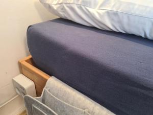 łóżko z niebieskim kocem i krzesłem obok niego w obiekcie Lichtdurchflutetes Zimmer - Marienberg w mieście Waldbüttelbrunn
