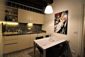 una cocina con mesa, fregadero y una pintura en San Marco charming apartment with canal view, en Venecia