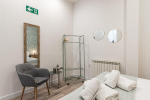 Cette chambre blanche dispose d'un miroir et d'une chaise. dans l'établissement BNBHolder Ponzano & Chamberi III, à Madrid