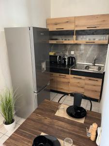 een keuken met een roestvrijstalen koelkast en een houten tafel bij Charcoal Thirteen Apartment in Kavala