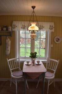 a dining room table with two chairs and a chandelier at Cozy Country House in Spydeberg
