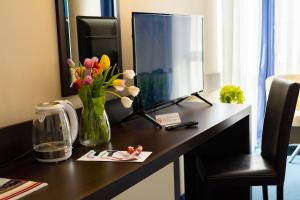 a desk with a computer monitor and flowers on it at Grami Hotel Sofia in Sofia