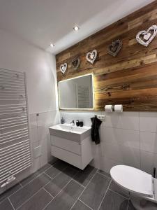 a bathroom with a sink and a mirror with hearts on the wall at Aparthotel Waldhorn Wohnung Allgäustyle in Stuttgart