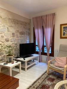 a living room with a tv and a stone wall at Casa Marinera "Tu casa de Baiona" in Baiona