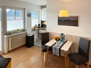 una cucina e una sala da pranzo con tavolo e sedie di Haus Diana *Ferienwohnung Kniepsand* a Wittdün