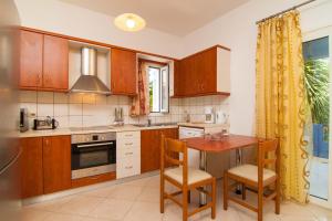 a kitchen with wooden cabinets and a table with chairs at Blue Villa 1 - With Private Pool in Perama