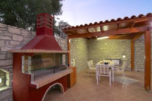 een patio met een buitenoven en een tafel met stoelen bij Blue Villa 2 - With Private Pool in Perama