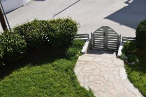 a bench sitting on the grass next to a sidewalk at Lefteris Apartments in Ialysos Rhodes in Ialysos