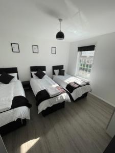 a room with three beds and a window at Monochrome Emerald in Brentwood