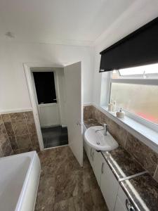 a bathroom with a sink and a toilet and a window at Monochrome Emerald in Brentwood