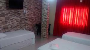 Hotel Dois Candangos في برازيليا: غرفة بسريرين وستارة حمراء