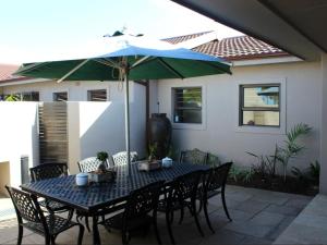 einen Tisch und Stühle mit Sonnenschirm auf einer Terrasse in der Unterkunft Two Oceans Stay in Kapstadt