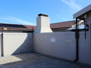 a white building with a gate and a garage at Two Oceans Stay in Cape Town