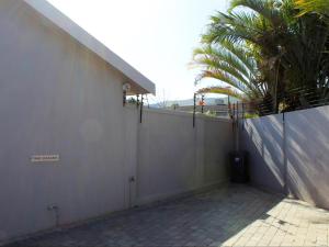 a white wall with a palm tree next to a building at Two Oceans Stay in Cape Town