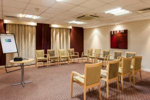 une salle de conférence avec des chaises et un podium dans l'établissement Holiday Inn Express London Stansted Airport, an IHG Hotel, à Stansted Mountfitchet