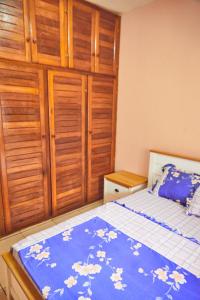 - une chambre avec un lit doté d'une couverture bleue et de placards en bois dans l'établissement Three rooms Appartment Bieyem assi, à Yaoundé