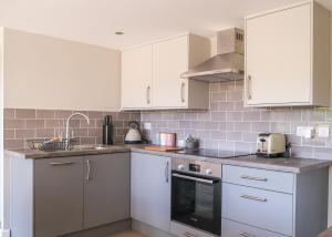 a kitchen with white cabinets and a sink at Converted Stable with Hot Tub in Ilkley