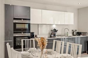 une cuisine avec une table et des chaises et une cuisine avec des placards blancs dans l'établissement Modern 2 Bed Apartment By Station Square, à Cambridge