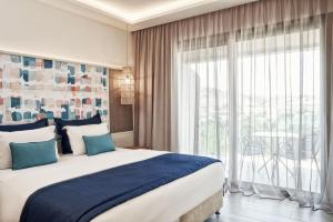a bedroom with a large bed and a large window at Atlantica Aegean Blue in Kolymbia +75 photos