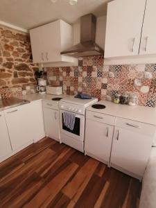 een keuken met witte kasten en een fornuis met oven bij le petit secret in Saint-Hilaire