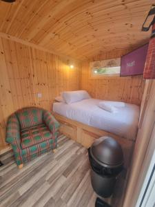 a bedroom with a bed and a chair in a cabin at Blair snug hut in Kelty