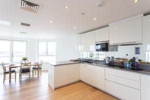 a kitchen with white cabinets and a dining room with a table at 2 Bed/2 Bath Penthouse With Amazing Views in London