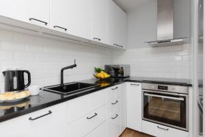 a white kitchen with a sink and a stove at Apartments Golden Warsaw by Noclegi Renters in Warsaw