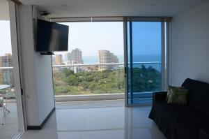 a living room with a tv and a large window at Tom Ocean Club con vista al mar piso 15 bello horizonte santa marta carrera 3 #110-55 bello orizonte santa marta in Gaira