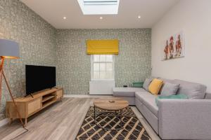 ein Wohnzimmer mit einem Sofa und einem TV in der Unterkunft The Cotswold Woodland in Cheltenham