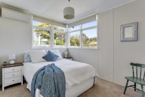a bedroom with a bed and a chair and windows at Bethany Bay Mount Martha in Mount Martha
