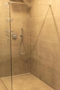 a shower with a glass door with a hose at Kadir Bey & Four Rooms in Osterrönfeld