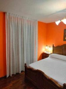 um quarto com paredes cor de laranja, uma cama e uma janela em Casa Brisas del Mar em Cabana de Bergantiños
