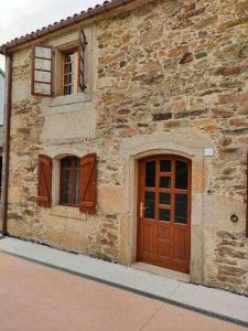 un edificio de piedra con puertas y ventanas de madera en Casa Brisas del Mar, en Cabana de Bergantiños