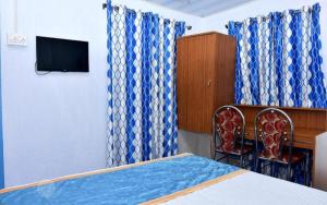 ムンナルにあるBlackcherry Munnarのベッドルーム(青いカーテン、ベッド1台、テレビ付)