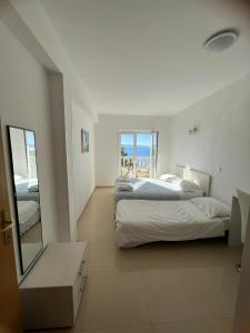 a white bedroom with two beds and a mirror at Brela Beachfront in Brela